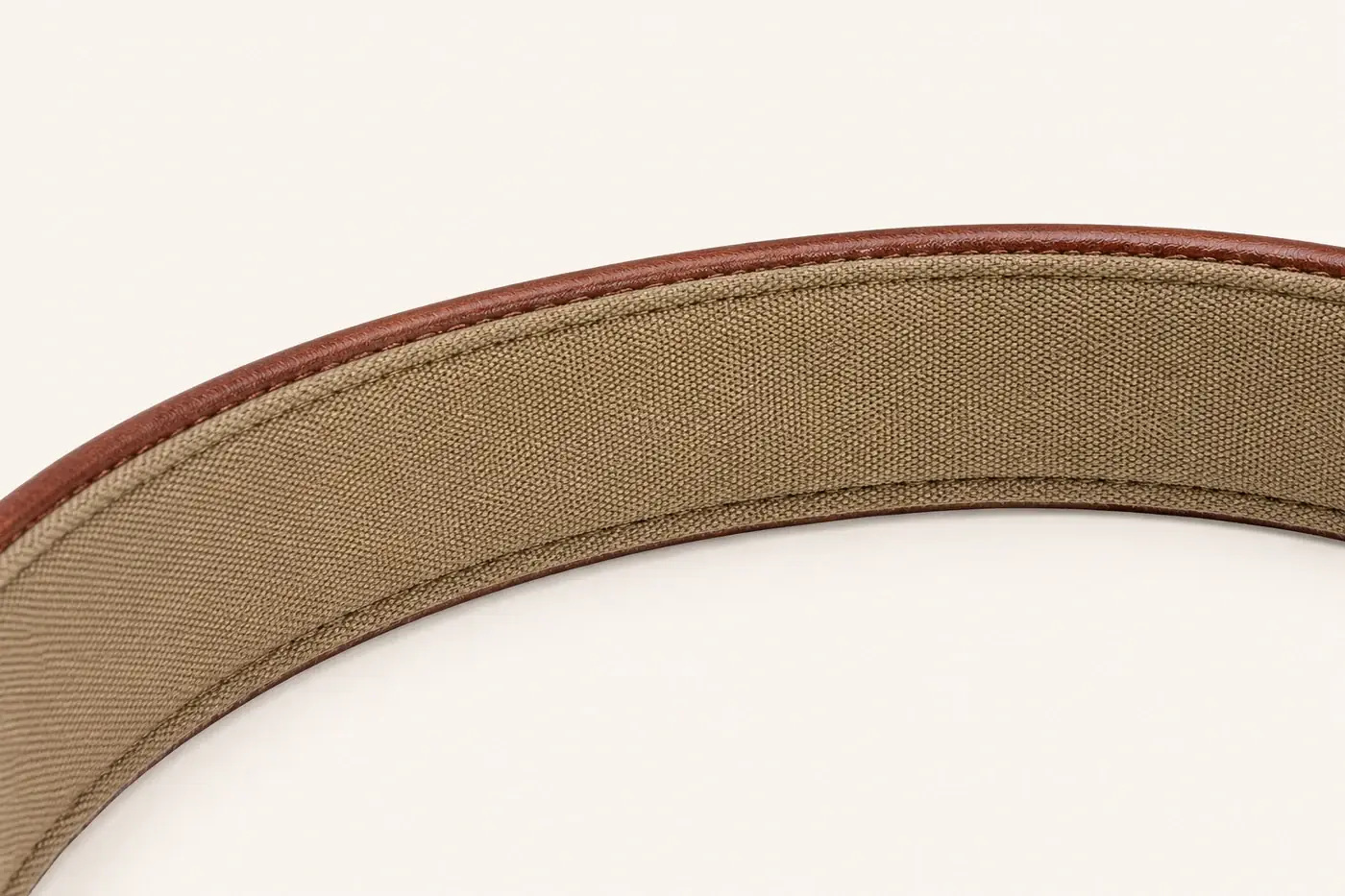 Extreme close-up of the collar strap curving away, showing the sand-colored woven lining stitched inside the brown leather edge
